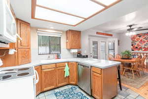 Kitchen featuring ceiling fan, white appliances, sink, and kitchen peninsula