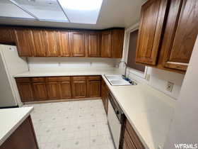 Kitchen featuring sink, fridge, light tile patterned floors, and white dishwasher