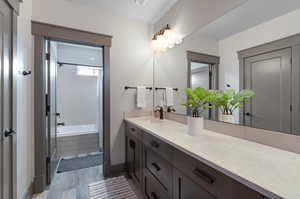 Bathroom with tiled shower / bath combo, vanity, and hardwood / wood-style floors