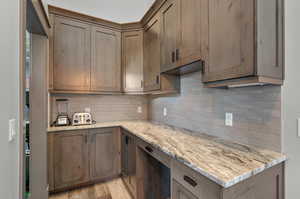 Kitchen featuring backsplash, light wood-type flooring, and light stone countertops