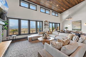 Living room featuring high vaulted ceiling, a notable chandelier, wood ceiling, and a fireplace