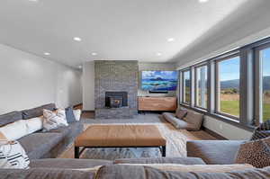 Carpeted living room featuring brick wall, a textured ceiling, and a brick fireplace