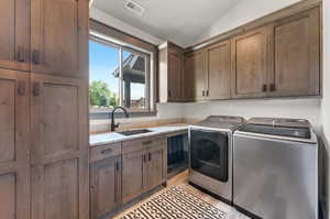 Laundry room with independent washer and dryer, light hardwood / wood-style flooring, sink, and cabinets