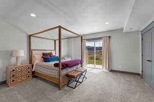 Bedroom with a textured ceiling, carpet flooring, and access to exterior