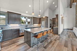 Kitchen featuring stainless steel appliances, a kitchen island, sink, tasteful backsplash, and light hardwood / wood-style flooring