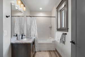 Bathroom with hardwood / wood-style flooring, vanity, and shower / bath combination with curtain