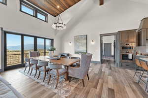 Dining room featuring a mountain view, high vaulted ceiling, wood ceiling, and light hardwood / wood-style floors