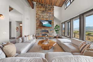 Living room with wooden ceiling, a stone fireplace, and high vaulted ceiling