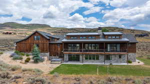 Back of property with a balcony, a mountain view, a patio area, and a yard