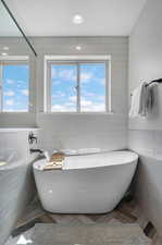 Bathroom with tile walls, a textured ceiling, and parquet floors