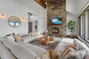 Living room featuring a towering ceiling, beamed ceiling, and a fireplace