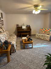 Carpeted living room with ceiling fan and a textured ceiling