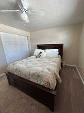 Bedroom featuring a textured ceiling, carpet, a closet, and ceiling fan