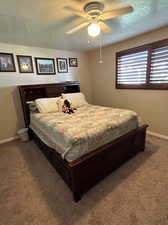 Bedroom featuring ceiling fan, a textured ceiling, and carpet