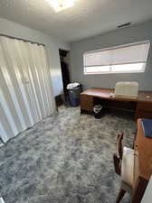 Carpeted bedroom with a textured ceiling and a closet