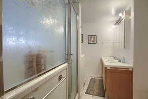 Bathroom featuring tile patterned floors, dual vanity, and an enclosed shower