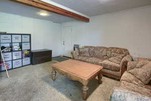 Carpeted living room featuring beam ceiling