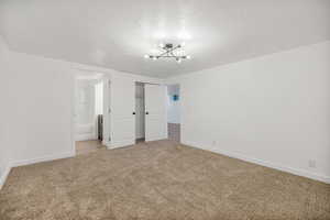 Primary bedroom, ensuite bathroom, light colored carpet, and a closet