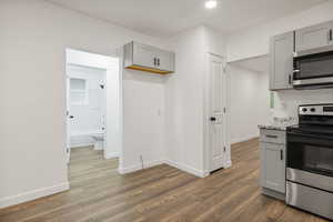 Kitchen featuring gray cabinetry, stainless steel appliances, dark wood-type flooring, and tasteful backsplash