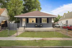 Bungalow-style home featuring a front yard and covered porch. Virtually added lawn.