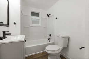 Main level Full bathroom with vanity, shower / tub combination, toilet, and hardwood / wood-style flooring