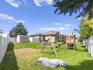 View of yard featuring a playground and a storage shed.