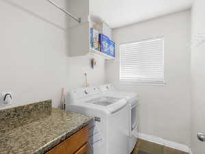 Laundry area featuring dark tile patterned floors and washing machine and clothes dryer.