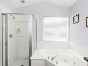 Master bathroom with light green colored walls and lofted ceiling and independent shower and bath.