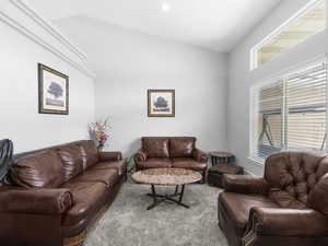 Carpeted seperate den/sitting area room with vaulted ceiling and carpeted floor.