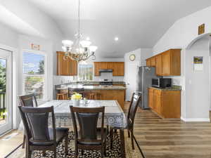 Dining space featuring sink, LVP floors, lofted ceiling, and a chandelier.