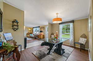 Dining area featuring hardwood / wood-style flooring, a textured ceiling, and ornamental molding