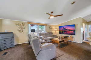 Carpeted living room with ceiling fan, vaulted ceiling, and a textured ceiling