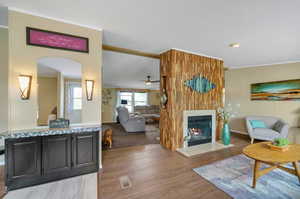 Living room featuring ceiling fan, wood-type flooring, a textured ceiling, and a large double sided fireplace