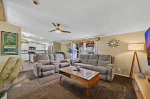 Carpeted living room featuring a textured ceiling and ceiling fan