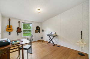 Home office with light hardwood / wood-style flooring and a textured ceiling