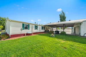 Rear view of property with a yard and a carport