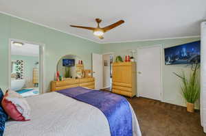 Bedroom with dark colored carpet, ceiling fan, a textured ceiling, and ensuite bathroom