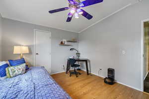 Bedroom featuring ceiling fan, wood-type flooring, and ornamental molding