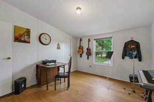 Office area with hardwood / wood-style floors, a textured ceiling, and lofted ceiling