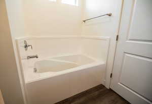 Bathroom with hardwood / wood-style flooring and a bath