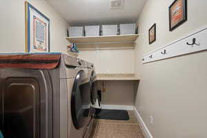 Main floor laundry area featuring washer and dryer, a textured ceiling, and tile patterned flooring