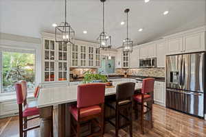 Kitchen with stainless steel appliances, white cabinetry, vaulted ceiling, tasteful backsplash, and sink