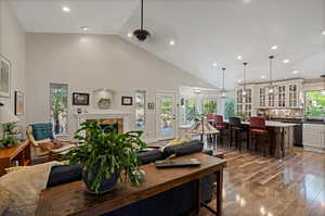 Dining space with high vaulted ceiling, ceiling fan, a fireplace, and hardwood / wood-style flooring