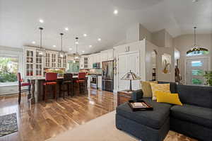 Living room with high vaulted ceiling, a chandelier, sink, and hardwood / wood-style flooring