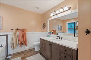 Master bathroom featuring toilet, tile walls, shower, vanity, and a washtub