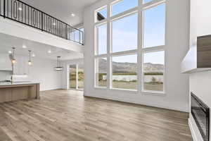 Unfurnished living room featuring light wood-type flooring, a mountain view, plenty of natural light, and a towering ceiling