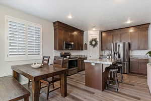 Kitchen featuring stainless steel appliances, a kitchen island with sink, sink, backsplash, and hardwood / wood-style flooring