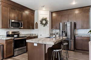 Kitchen featuring a center island with sink, light wood-type flooring, sink, and stainless steel appliances