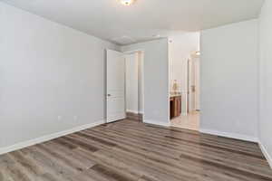 Primary BR: Unfurnished bedroom featuring ensuite bath and hardwood / wood-style flooring