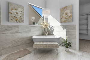 Bathroom with an inviting chandelier, tile walls, and a tub